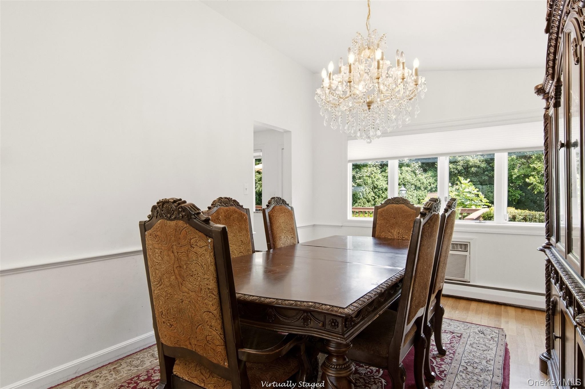 Hardwood flooring, crown molding, chair rail, and an ornate crystal chandelier illuminate the space