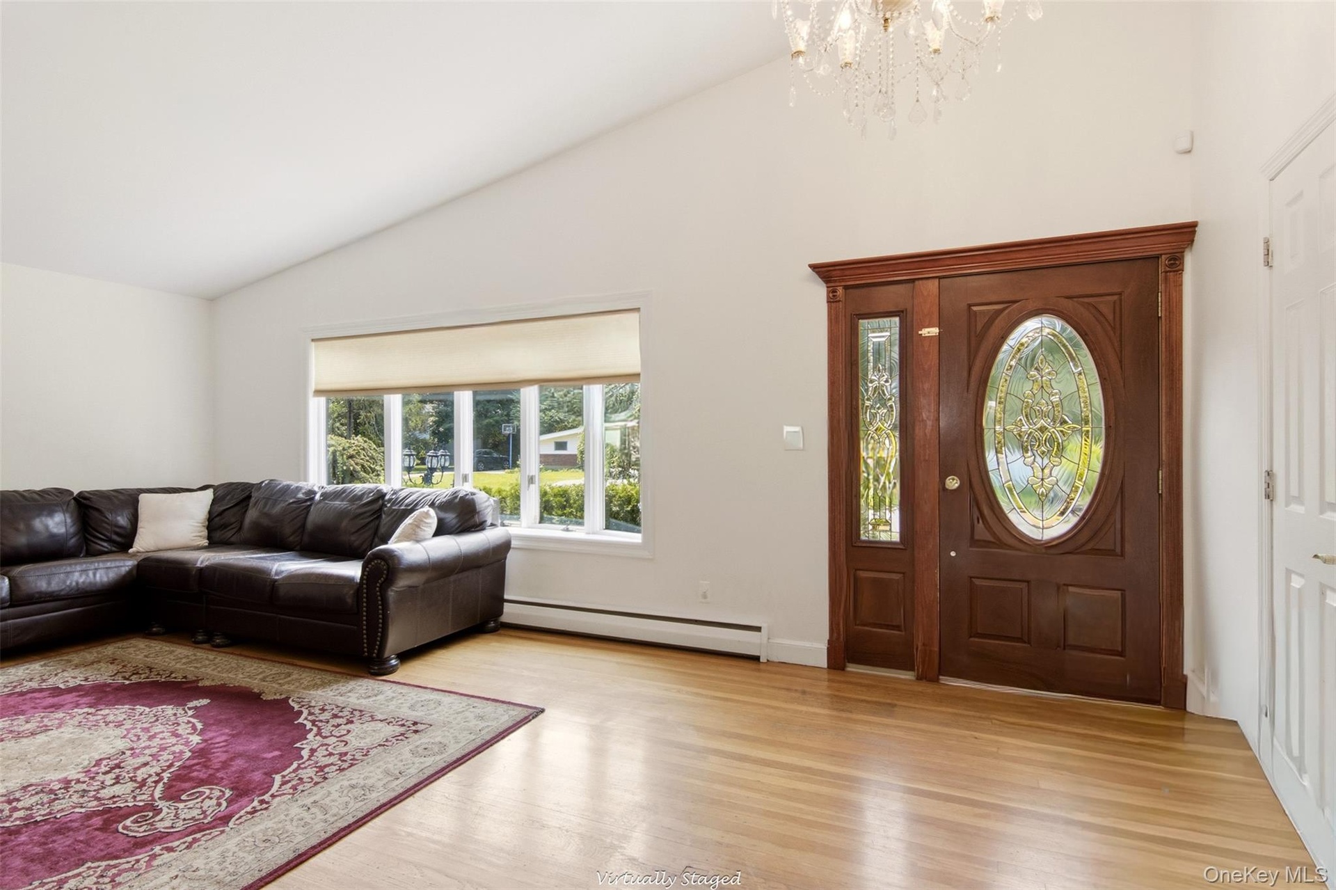 Hardwood flooring, vaulted ceiling, large picture window, and an ornate front door with sidelight