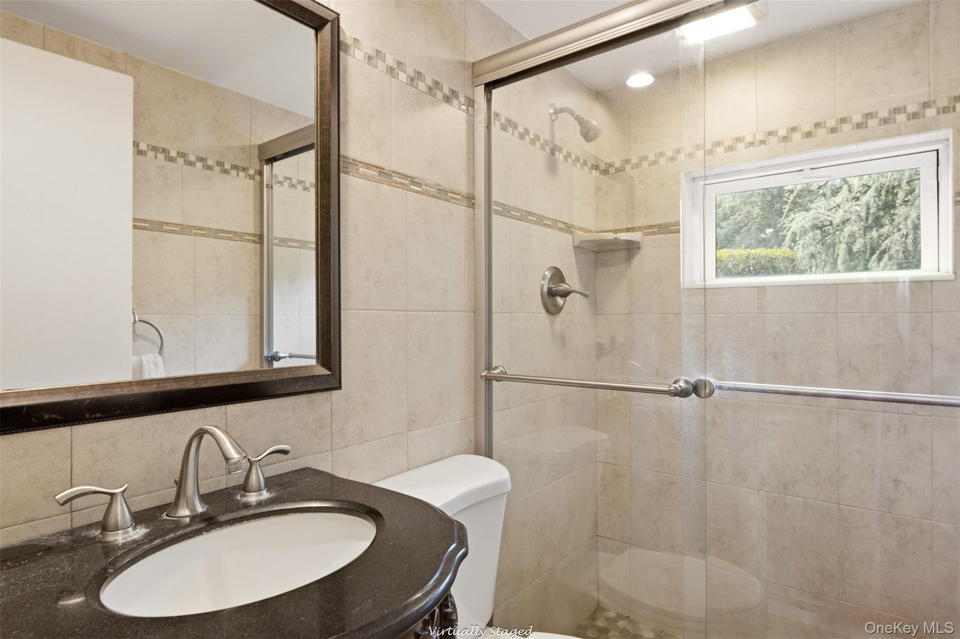 Glass-enclosed shower with pebble-finish flooring