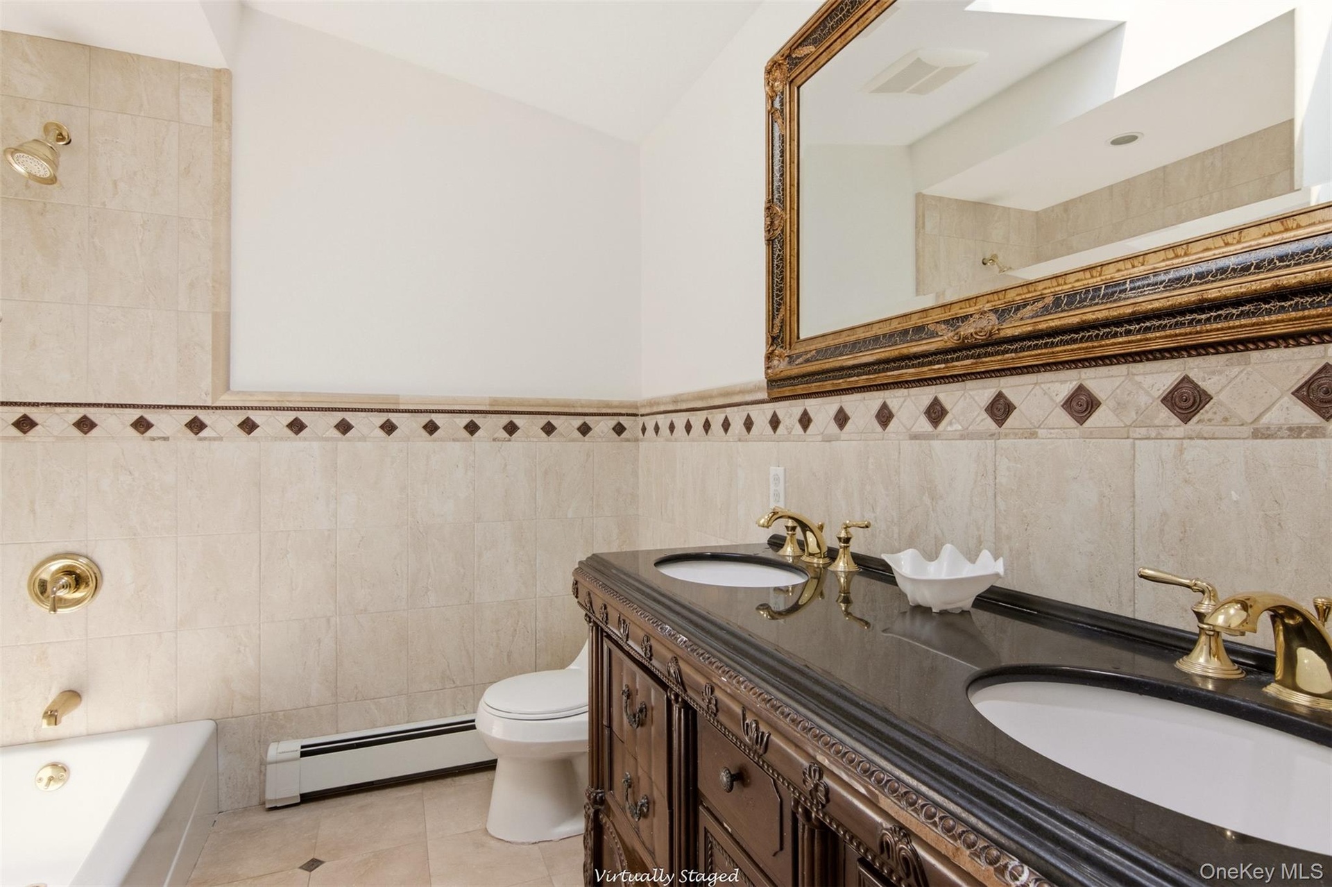 Dual vanity with dark countertop, ornate wood-finish cabinetry, and gold-tone fixtures