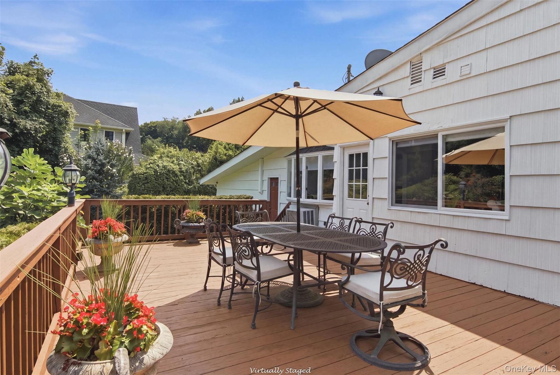 Expansive wood-finish deck with a wood railing and a white shingle exterior