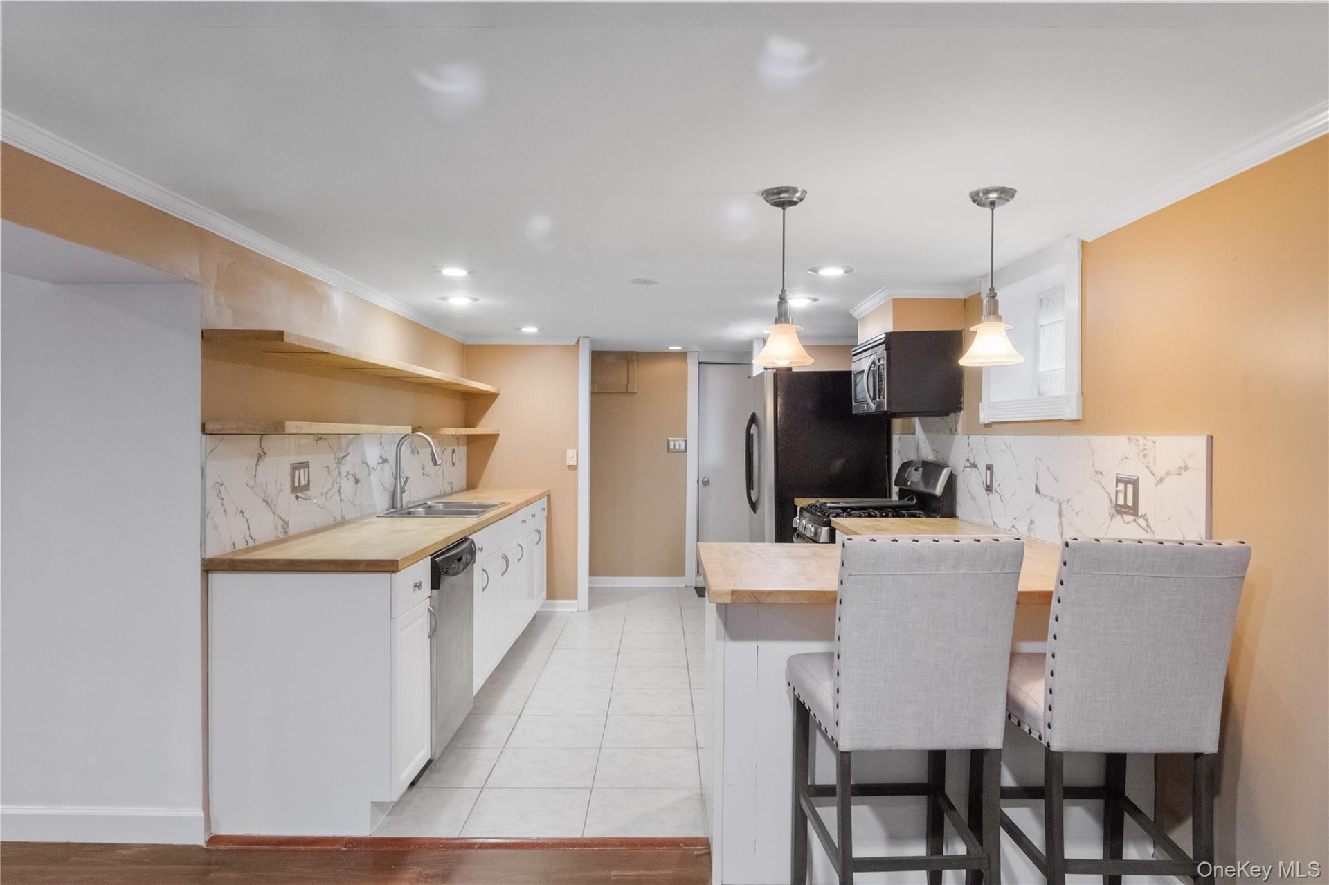This bright and airy lower level kitchen features butcher block countertops and stainless steel appliances.