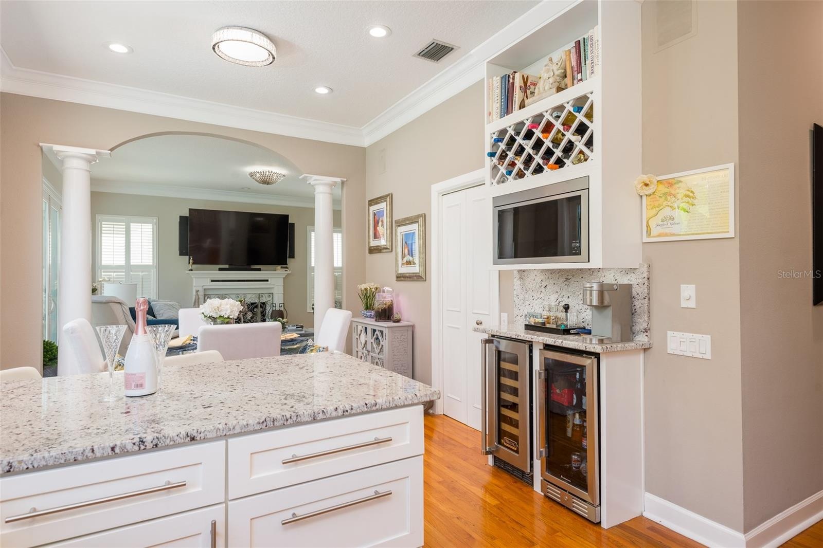 View from kitchen into breakfast room and living room Built in Recipe Book Shelf, wine rack, microwave oven, coffee bar, wine cooler, beverage cooler 
