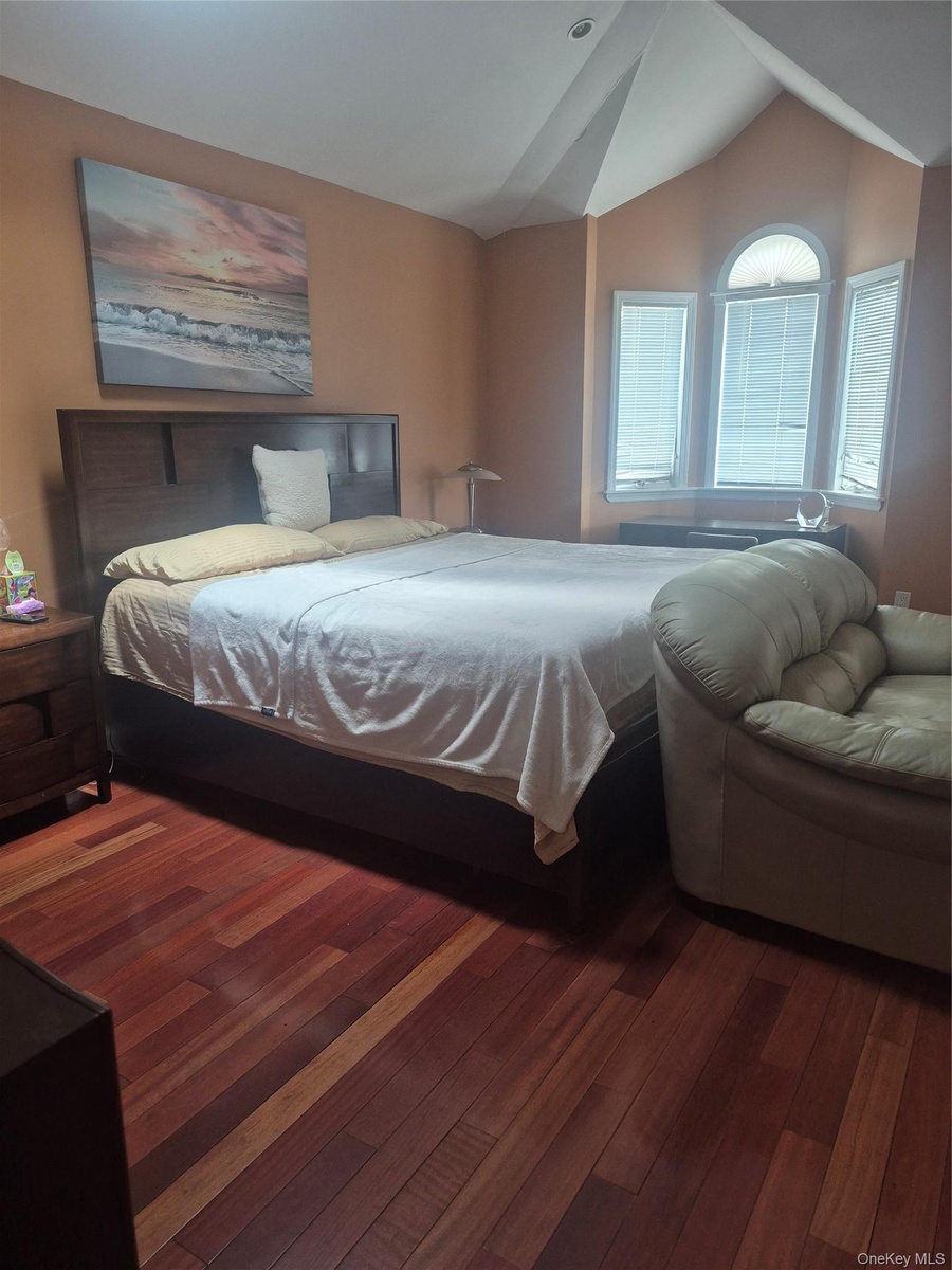 Master Bedroom with wood-finish flooring, recessed lighting, a vaulted ceiling and arched bay window