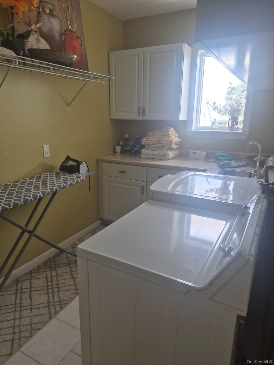Laundry area with light-colored cabinetry, a utility sink, and a window with washer/dryer combo.