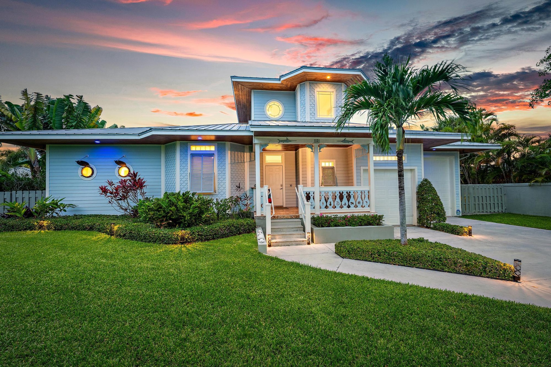Contemporary exterior with multi-level roofline, prominent front porch, attached garage, and mature palm tree