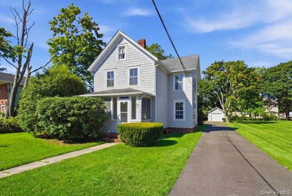 Two-story residence with shingle siding, a screened porch, and a paved driveway leading to a detached garage