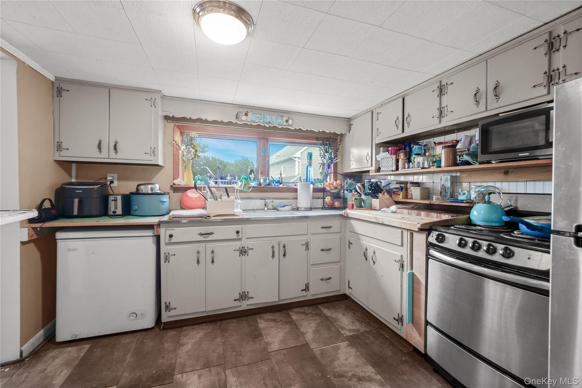 Kitchen featuring wood-finish flooring, white cabinetry, stainless steel range, dishwasher