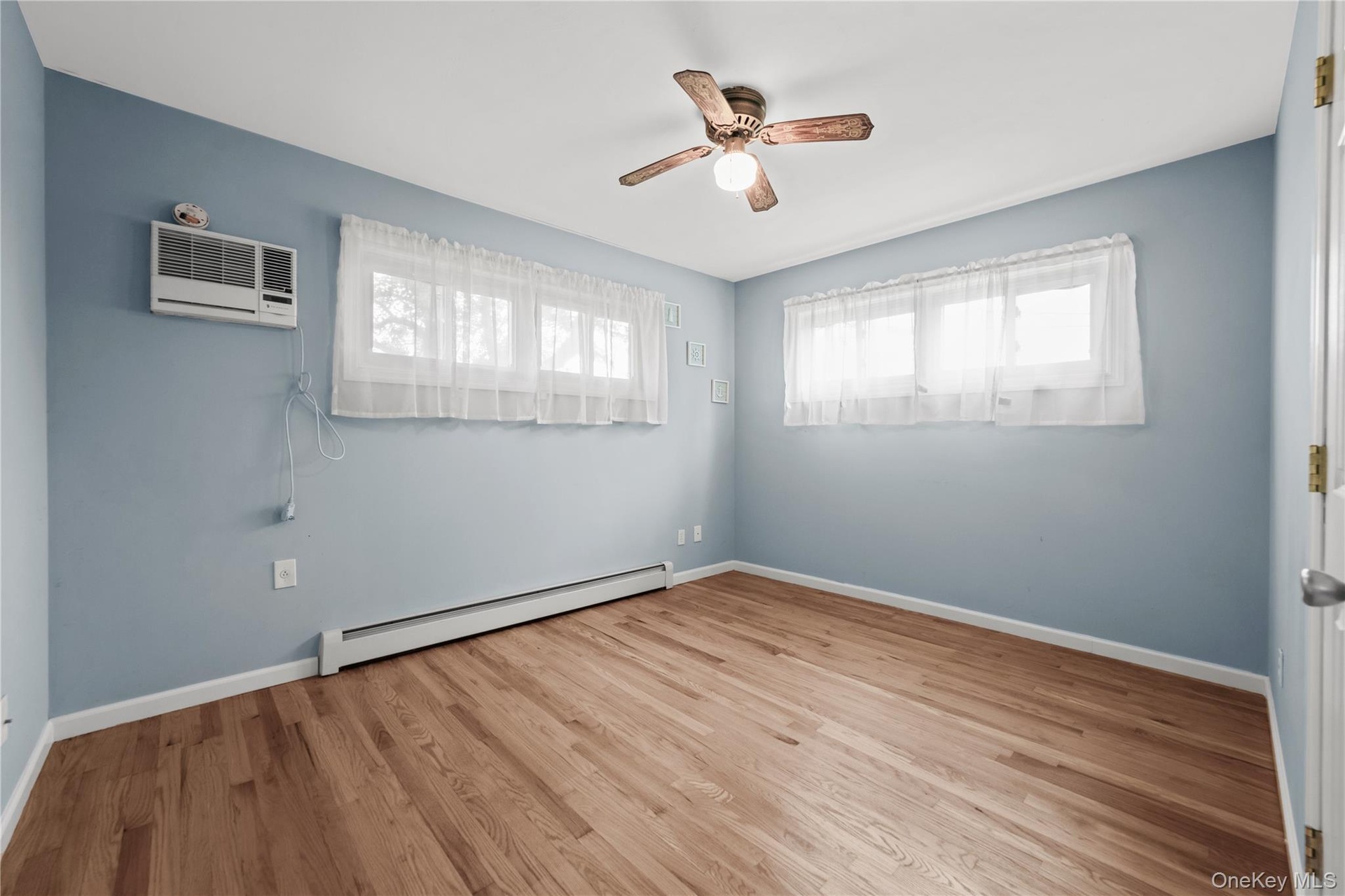 2nd. bedroom Hardwood flooring, ceiling fan, window treatments, and a wall-mounted air conditioning unit