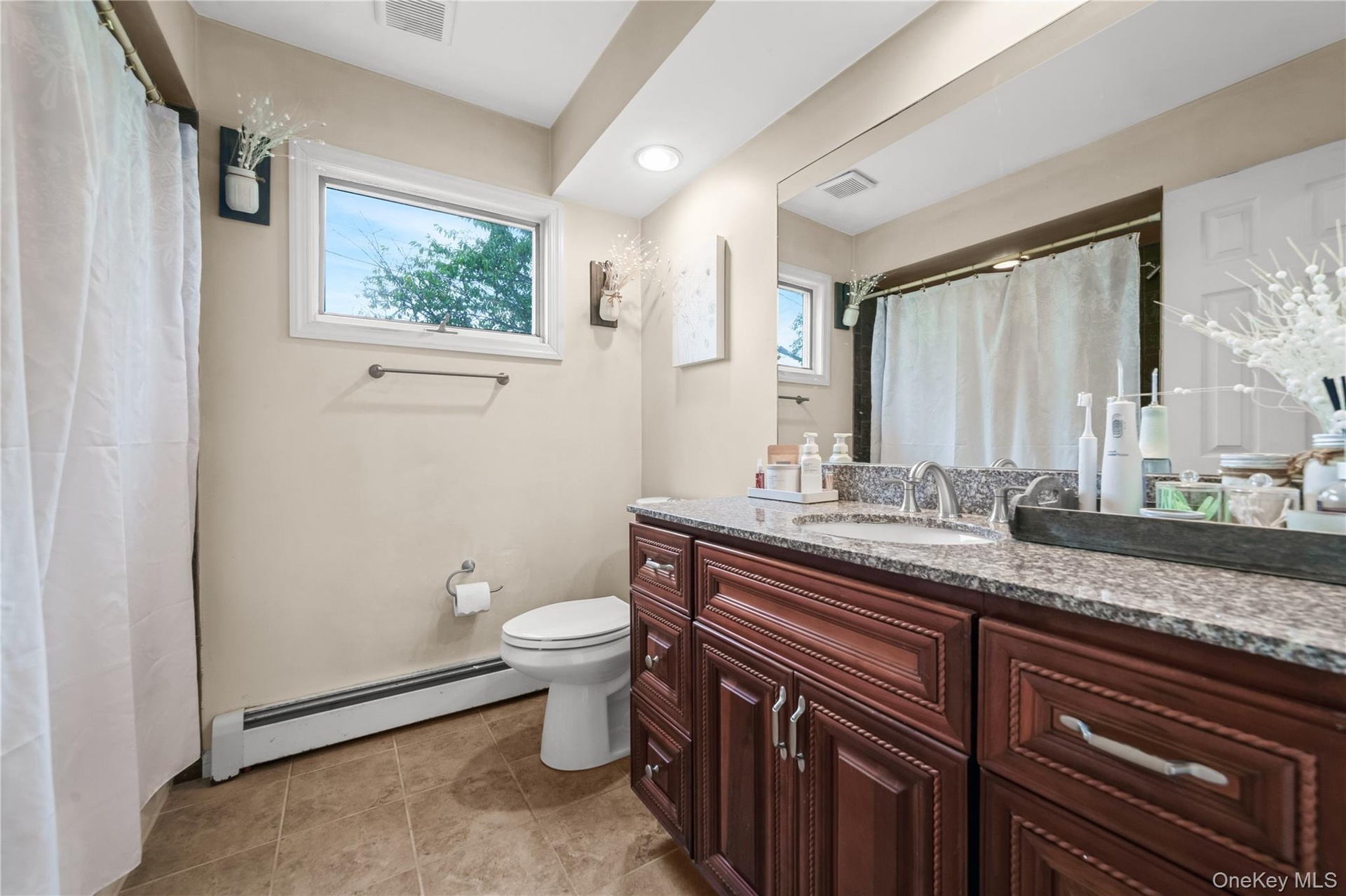 Bathroom featuring a wood-finish vanity with a granite countertop, undermount sink, and tile flooring