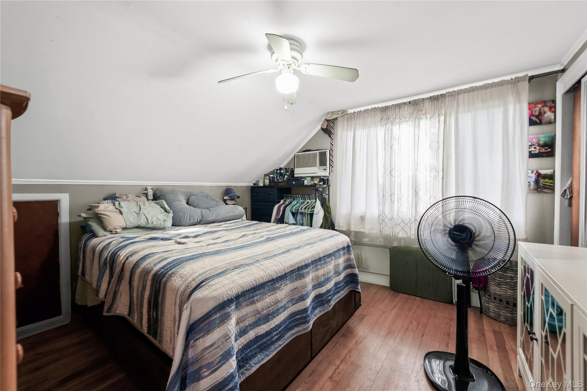 Unit 1 BedroomWood-finish flooring, ceiling fan, window-mounted air conditioning unit, and built-in shelving