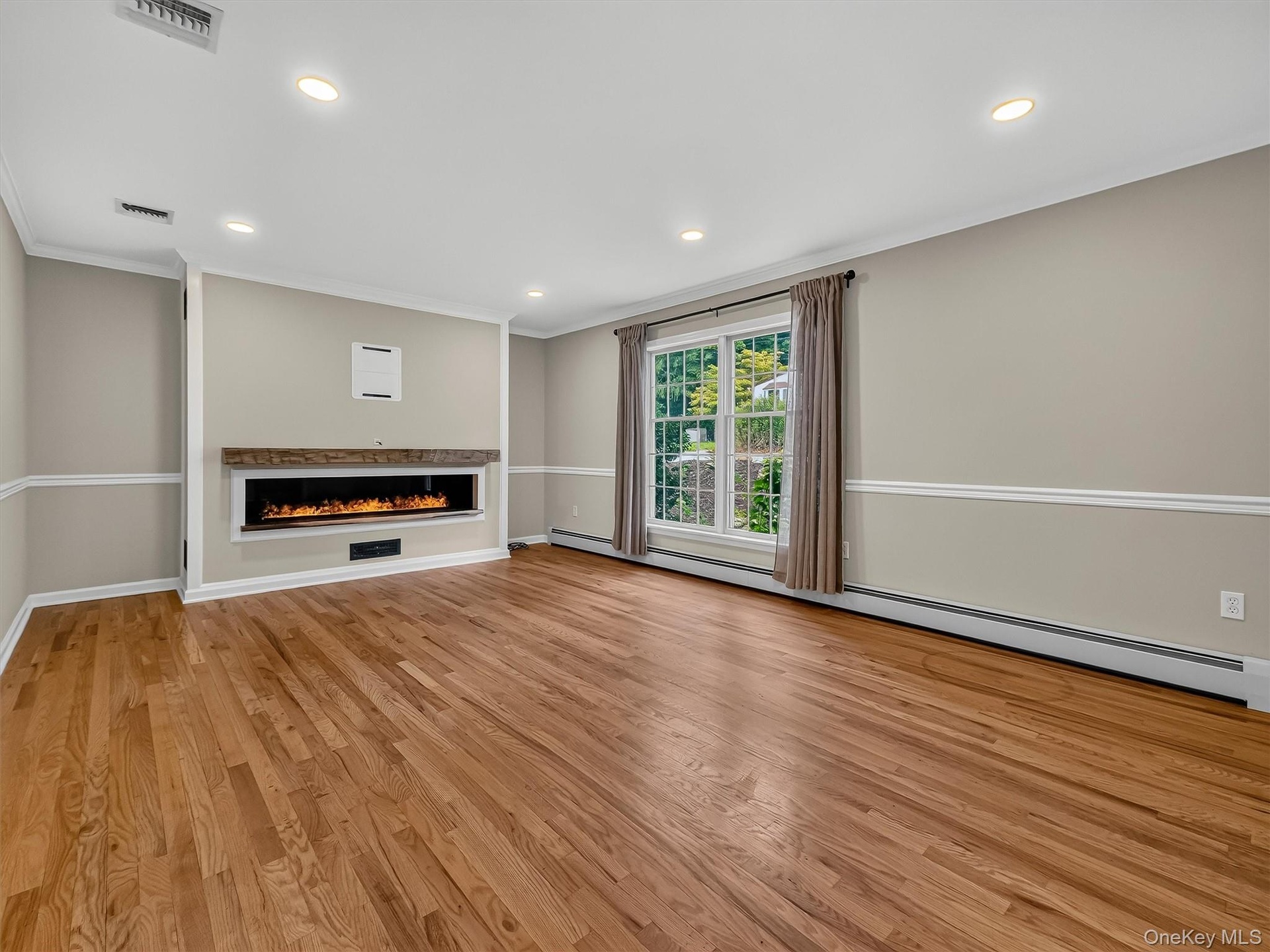 The spacious living room offers an inviting setting for everyday living and entertaining, enhanced by custom millwork, hardwood floors, and a stunning