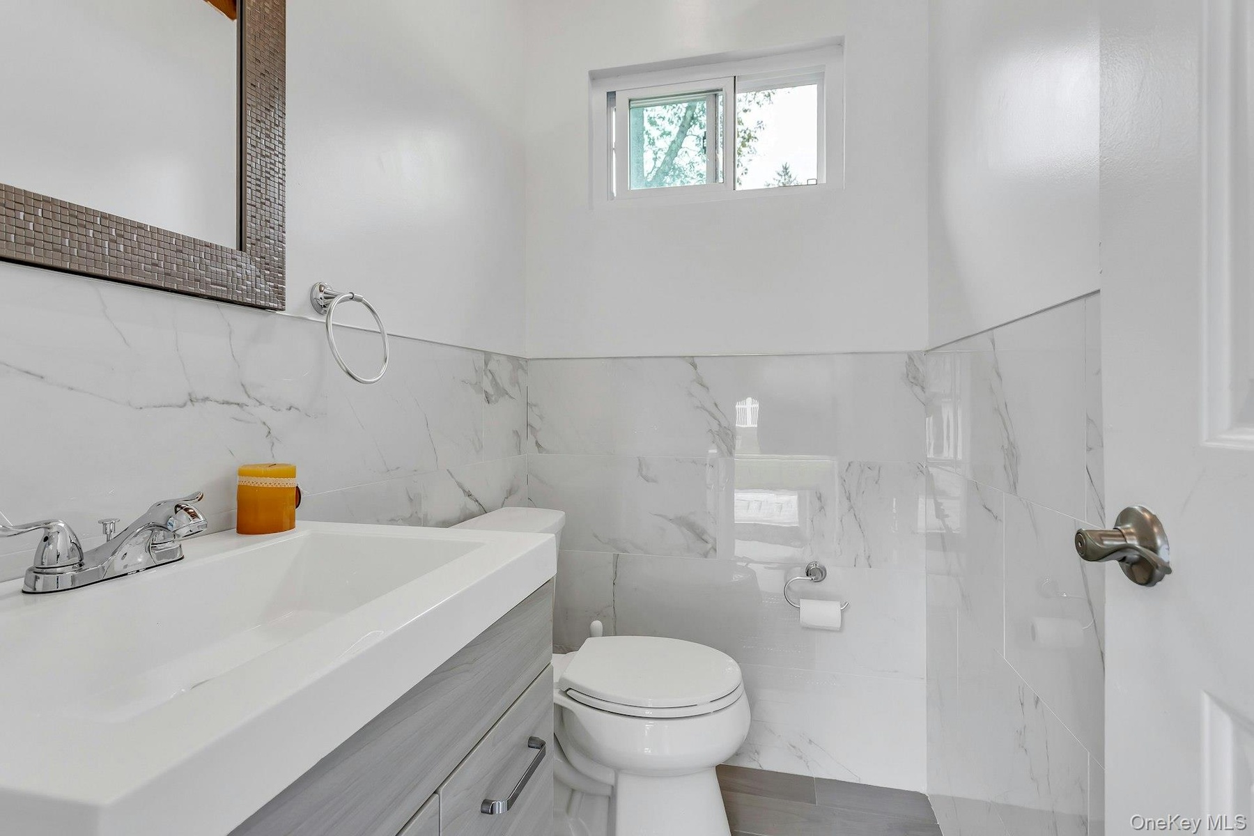 Bathroom featuring tile walls, vanity, and toilet