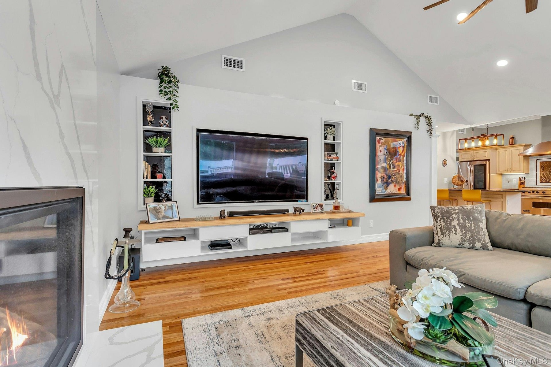 Living area with built in features, wood finished floors, recessed lighting, high vaulted ceiling, and baseboards
