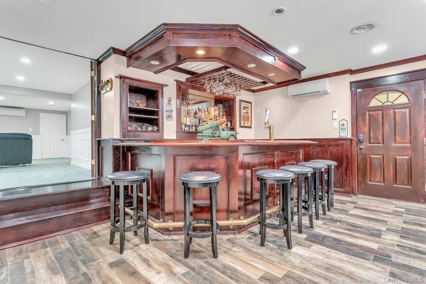 Indoor wet bar featuring a wall unit AC, a wainscoted wall, wood finished floors, a decorative wall, and ornamental molding