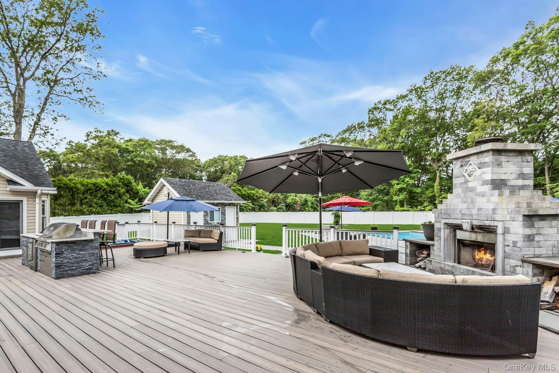 Wooden terrace with an outdoor living space with a fireplace and a fenced backyard