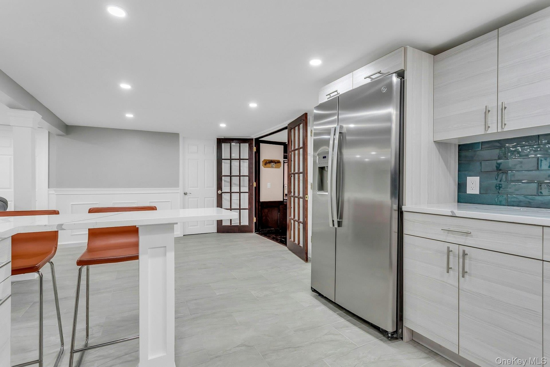 Kitchen with stainless steel refrigerator with ice dispenser, a breakfast bar, recessed lighting, wainscoting, and light marble finish flooring