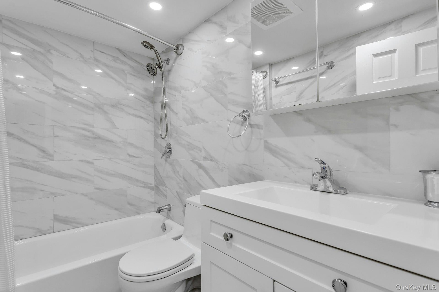 Full bathroom featuring vanity,  shower combination, tile walls, toilet, and recessed lighting