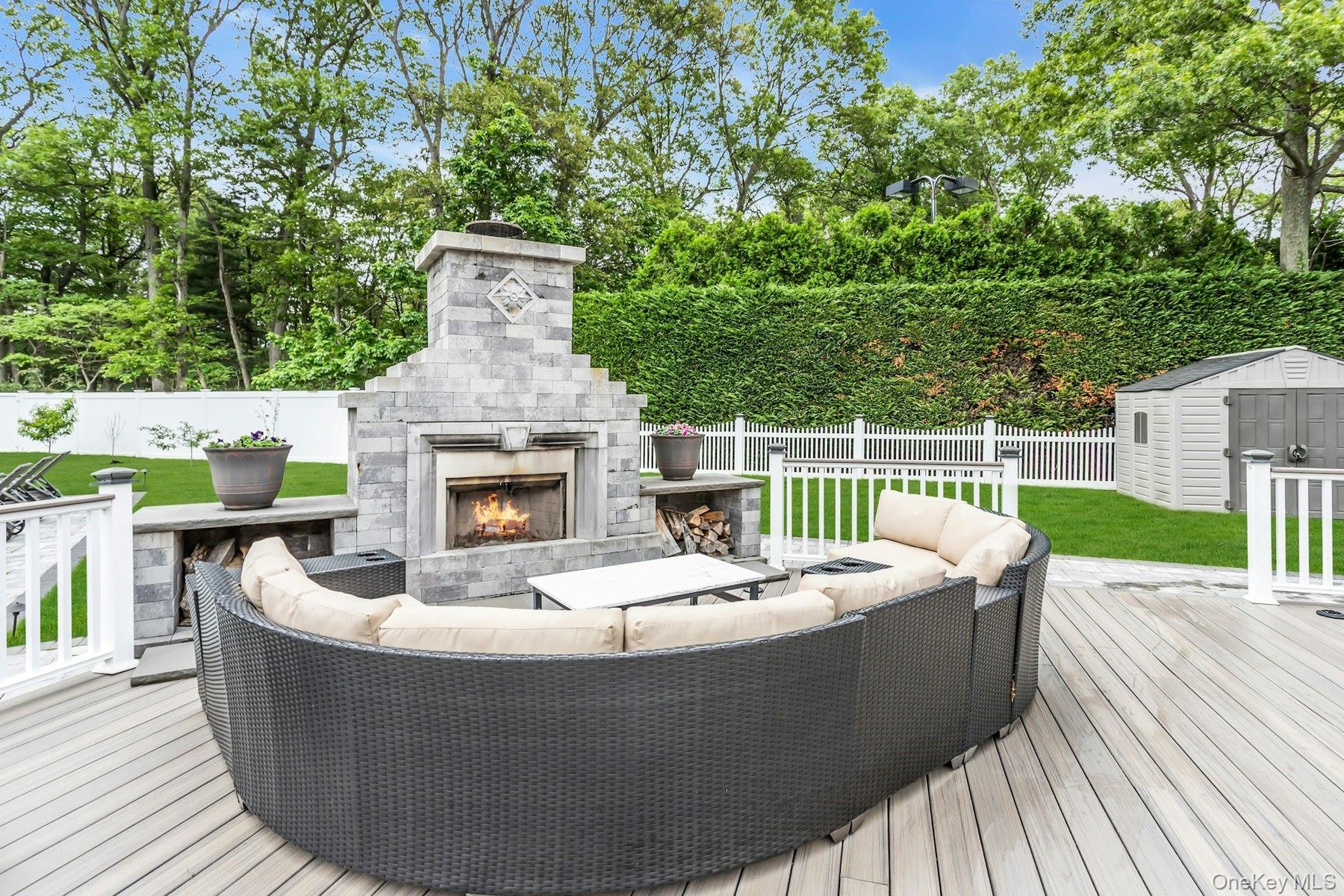 Wooden terrace featuring an outdoor living space with a fireplace and view of wooded area