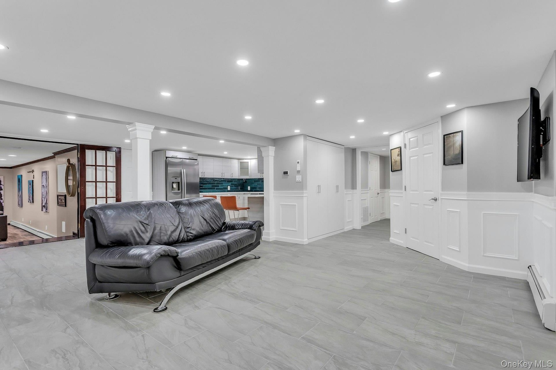 Living room with decorative columns, a decorative wall, recessed lighting, wainscoting, and a baseboard heating unit