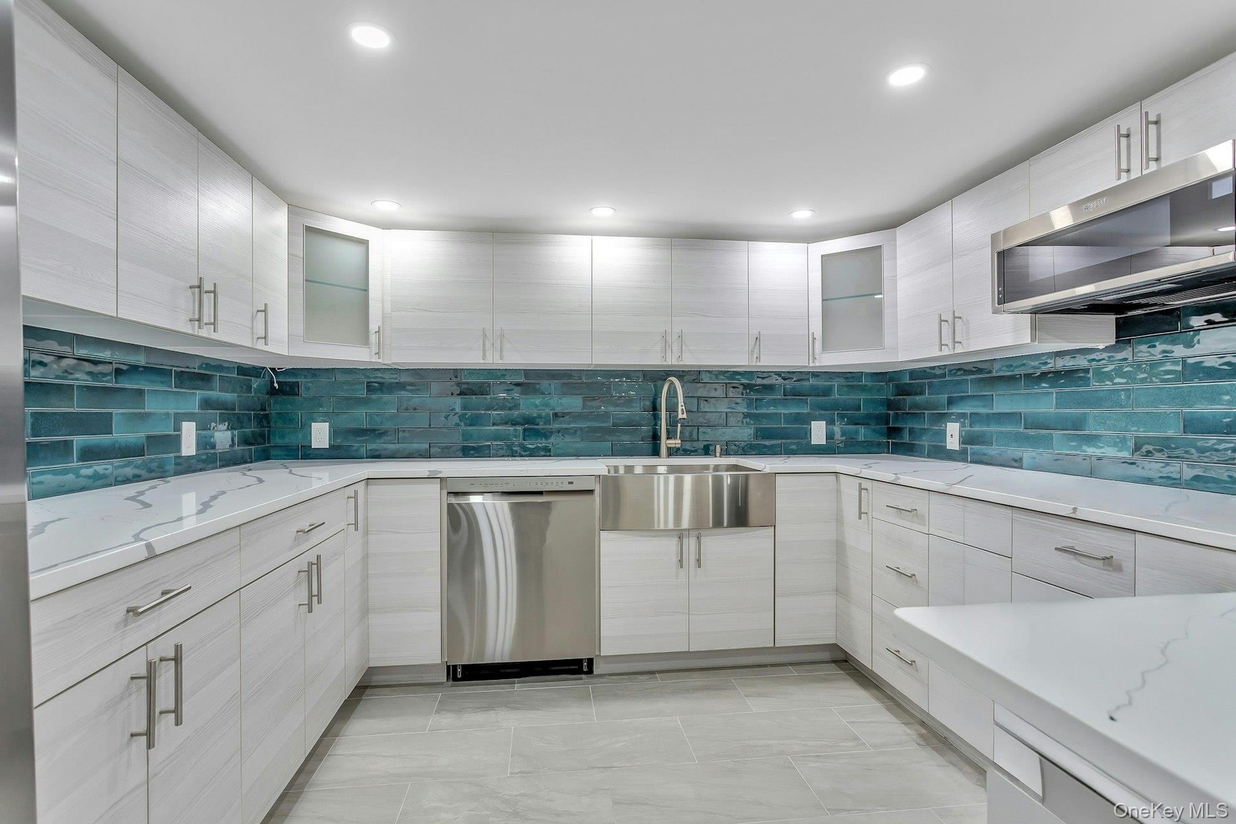 Kitchen with appliances with stainless steel finishes, a sink, tasteful backsplash, glass insert cabinets, and recessed lighting