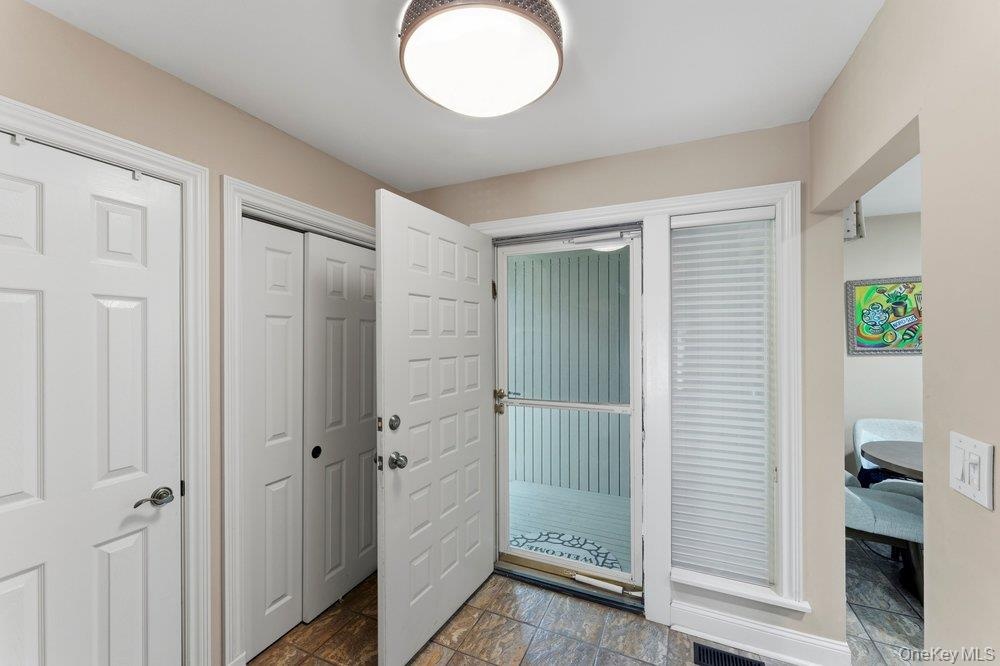 Entry way featuring tiled flooring, a flush-mount ceiling light, white paneled doors, and a front entry door with an adjacent window