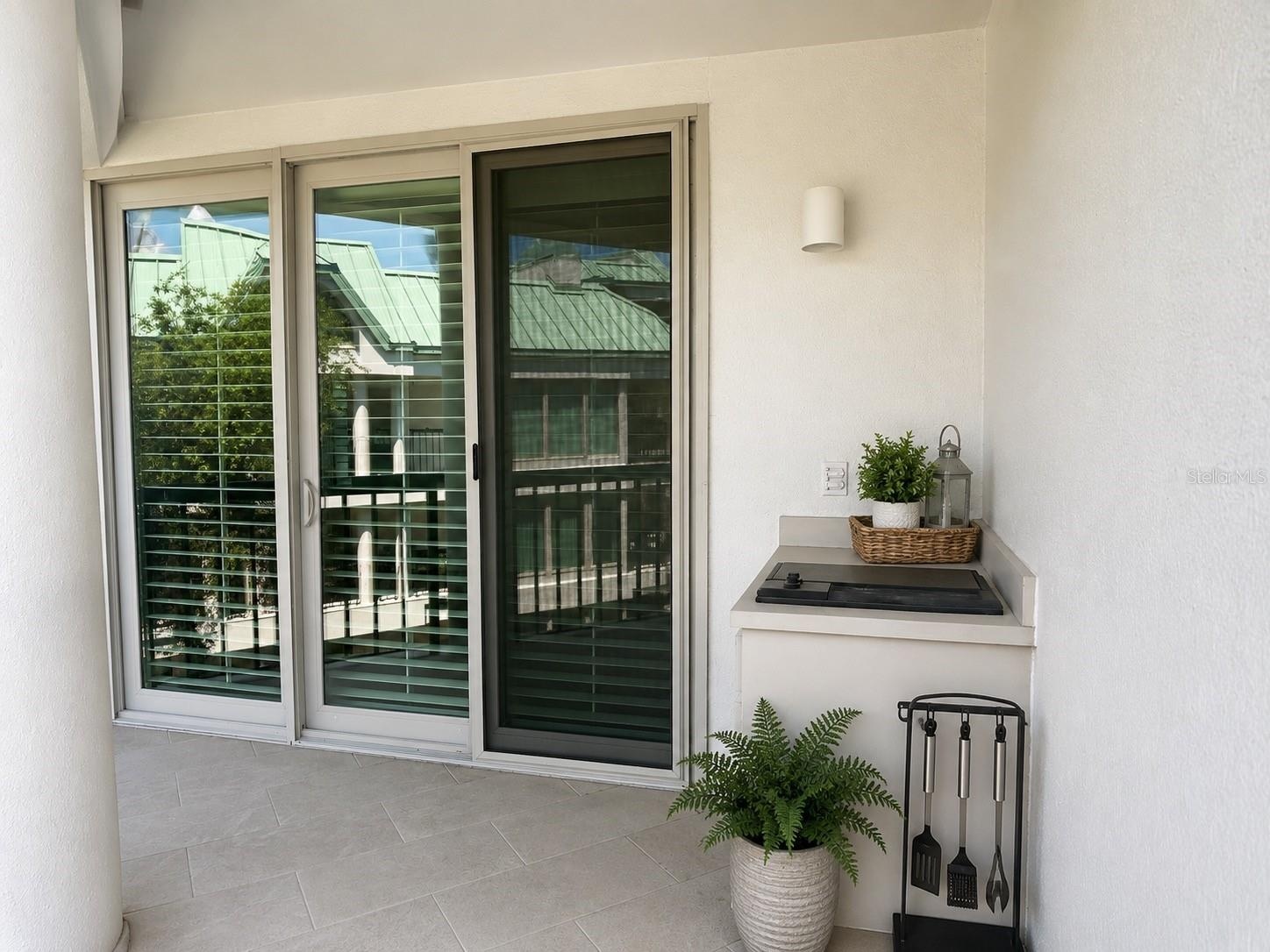 Grill area on wraparound first-level balcony. Sliding glass doors leading to 1st floor primary bedroom in background.