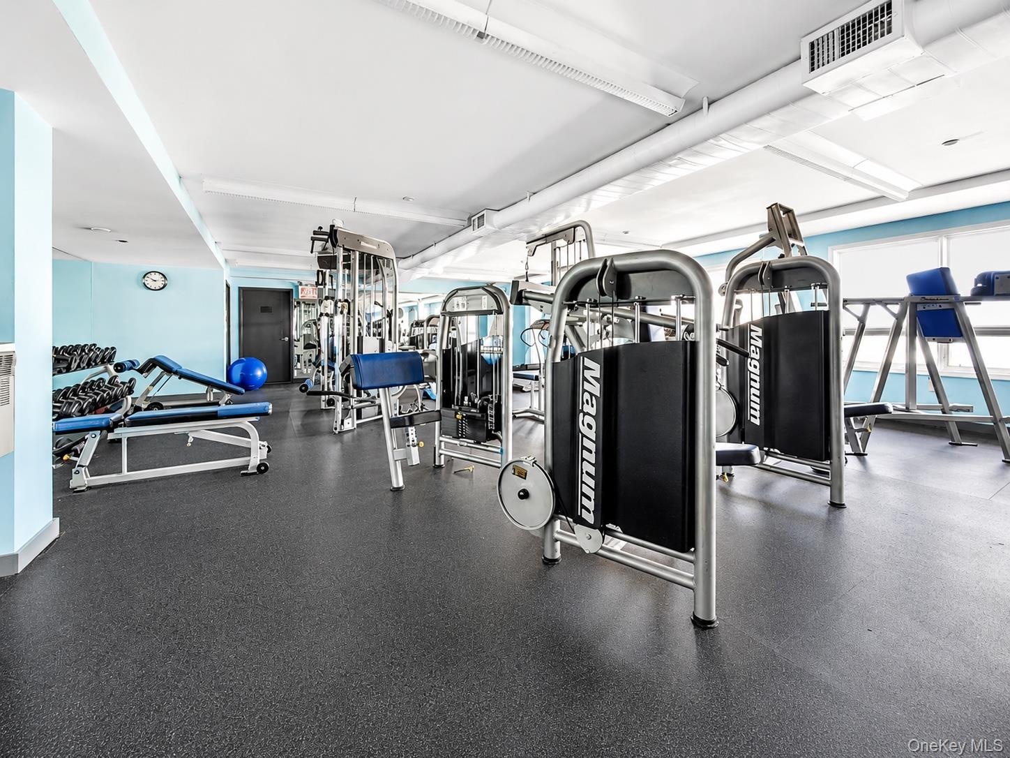 Fitness area featuring rubber flooring, recessed lighting, and blue accent walls