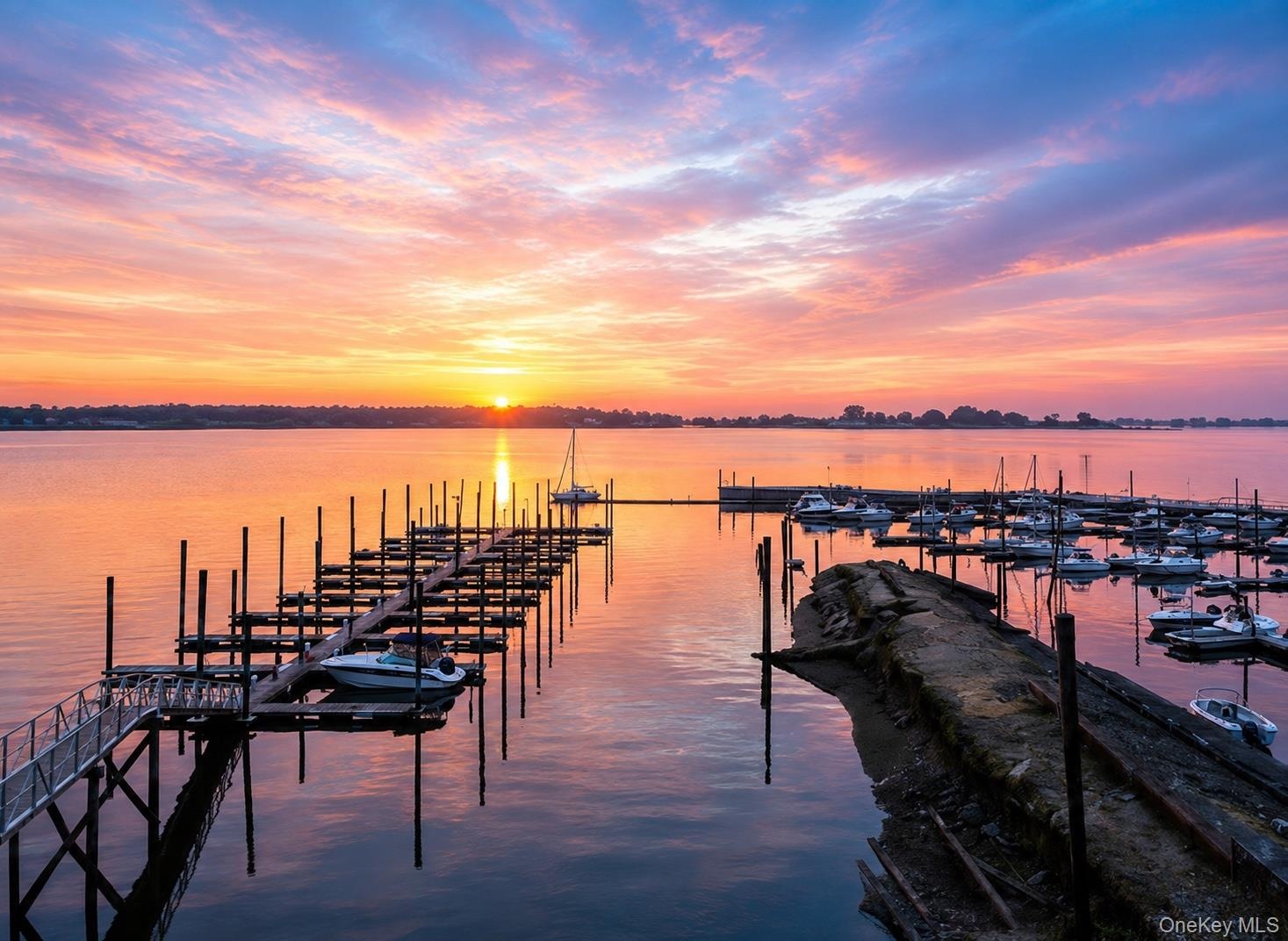 Waterfront setting featuring a marina with multiple boat slips and a lengthy dock structure