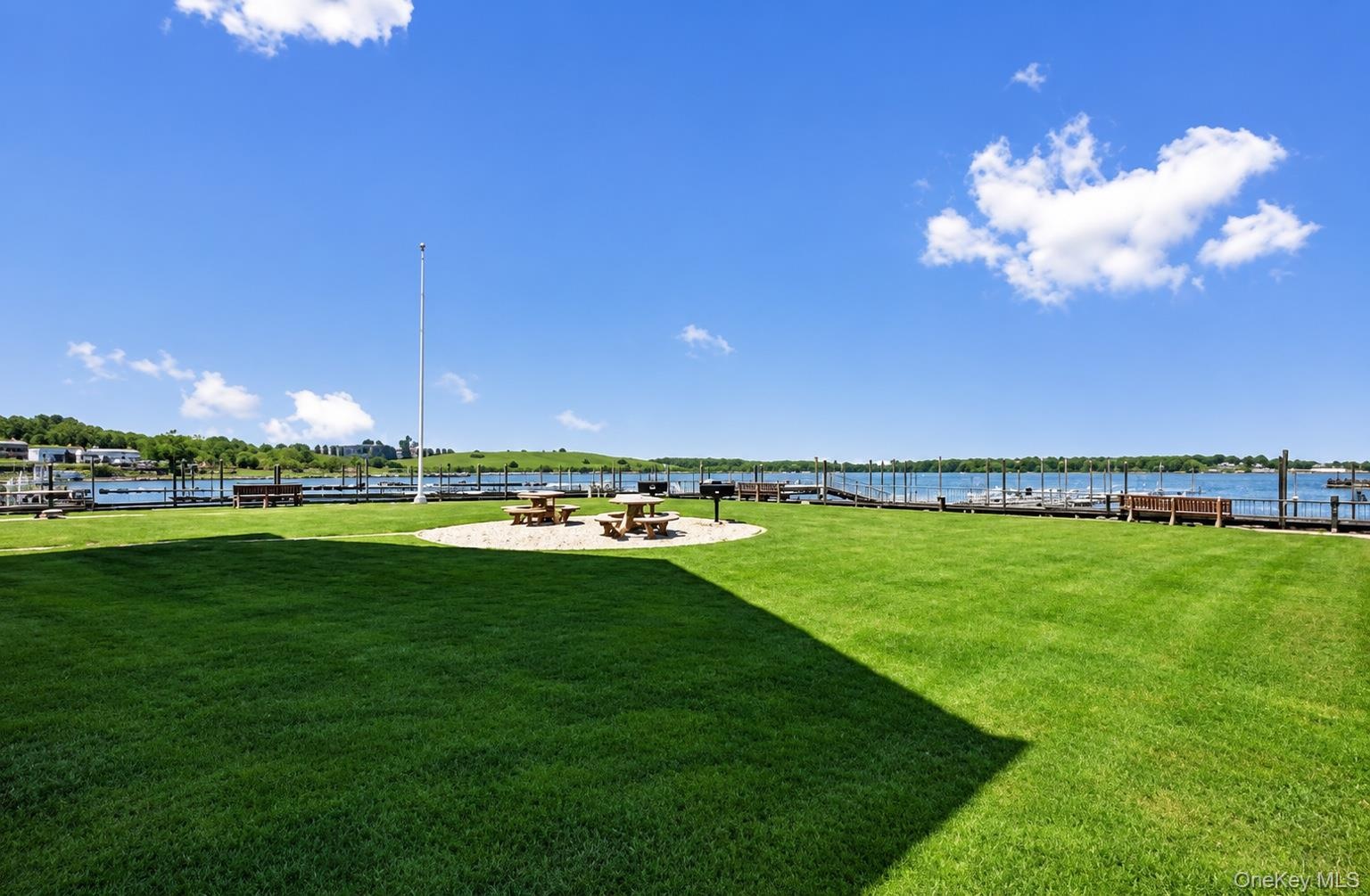 Expansive lawn area with a gravel seating area, a built-in grill, and water access with multiple boat slips