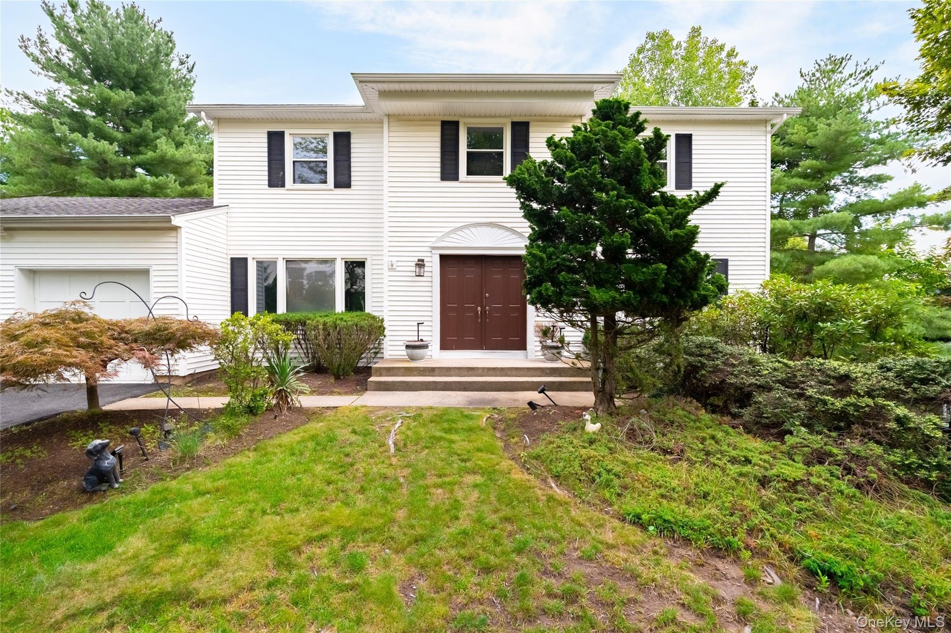 White siding exterior with dark shutters, a two-car garage, and a brown double entry door