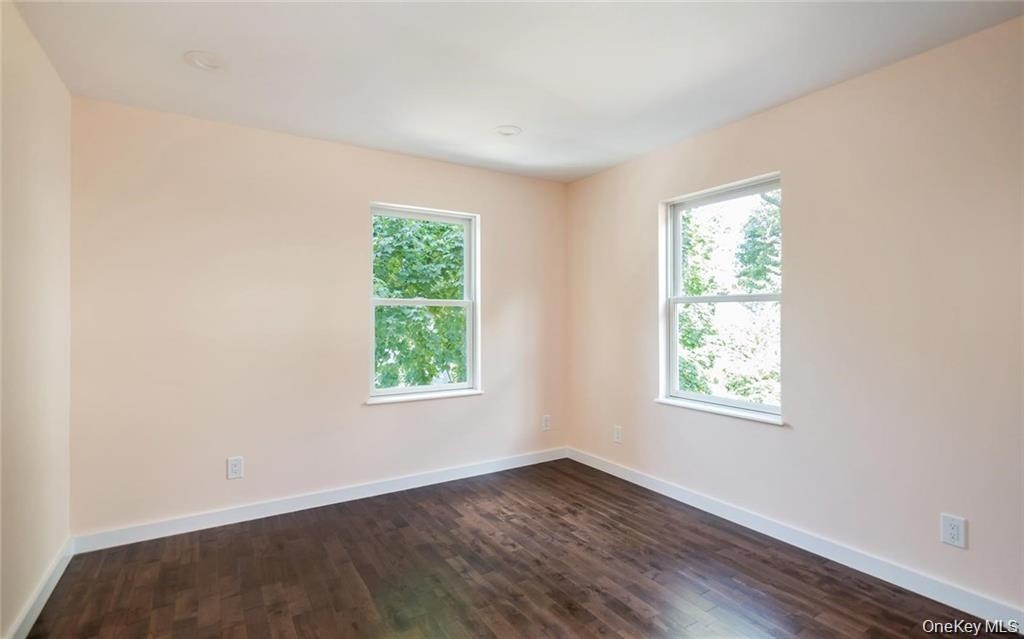 Spare room with dark wood-style floors and plenty of natural light