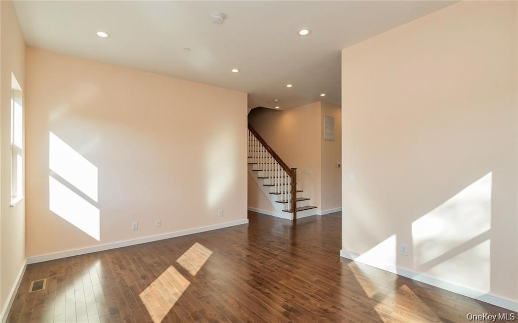 Empty room featuring recessed lighting, stairway, and dark wood-style flooring