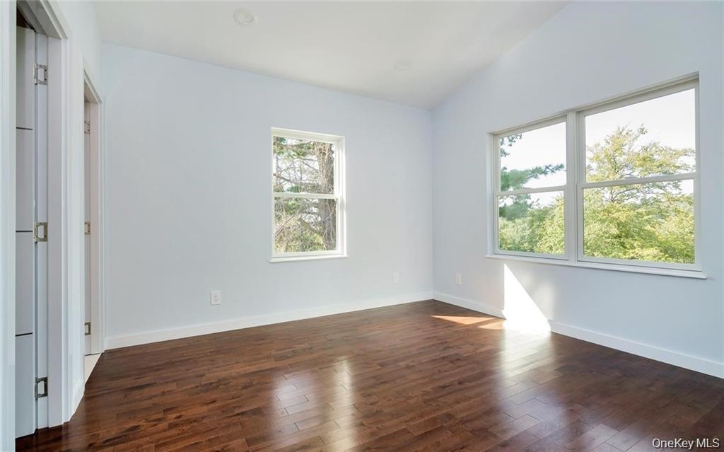 Unfurnished bedroom with dark wood-type flooring and vaulted ceiling