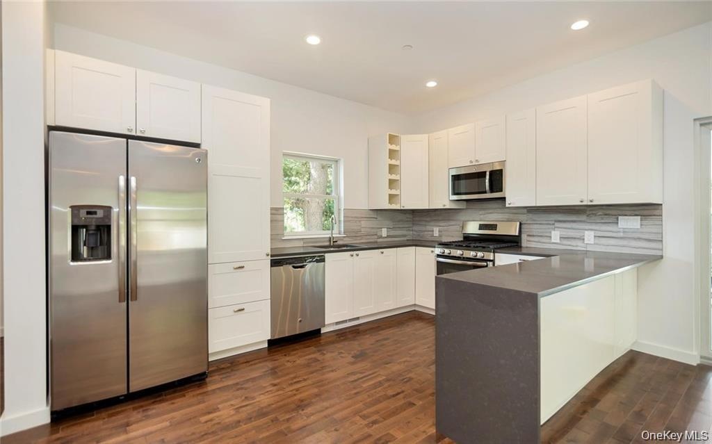 Kitchen with stainless steel appliances, open shelves, white cabinetry, recessed lighting, and dark wood-type flooring