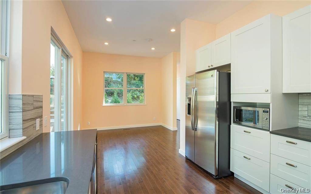 Kitchen featuring dark countertops, appliances with stainless steel finishes, white cabinets, dark wood-style floors, and recessed lighting