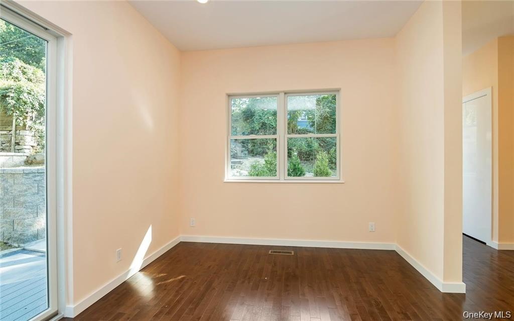 Empty room featuring dark wood-style flooring and baseboards