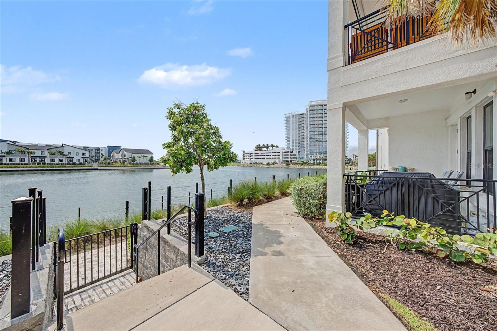 Gated entry to a paved waterfront walkway, perfect for a scenic stroll along the water.