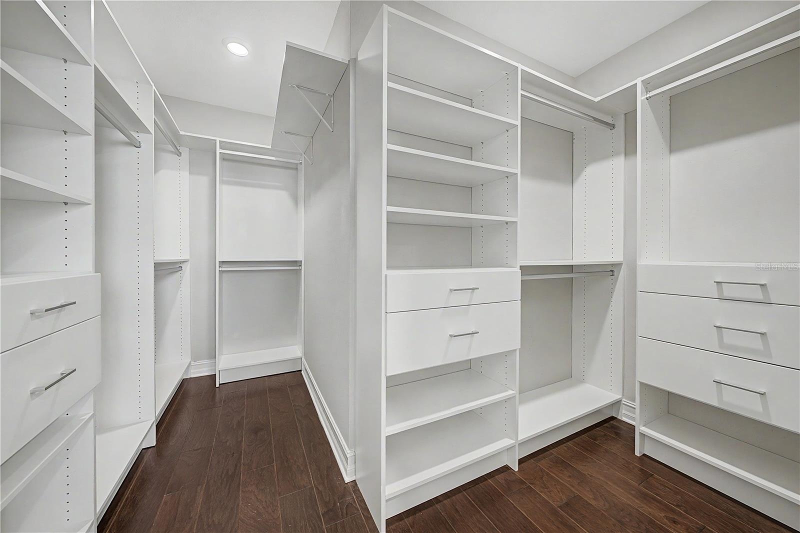 Spacious primary suite closet featuring professional custom built-in cabinetry and shelving.Spacious master closet featuring custom built-in cabinetry