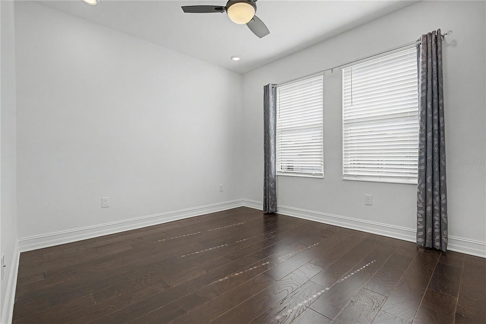 Third-level secondary bedroom offering a bright, comfortable space with abundant natural light from east-facing windows.