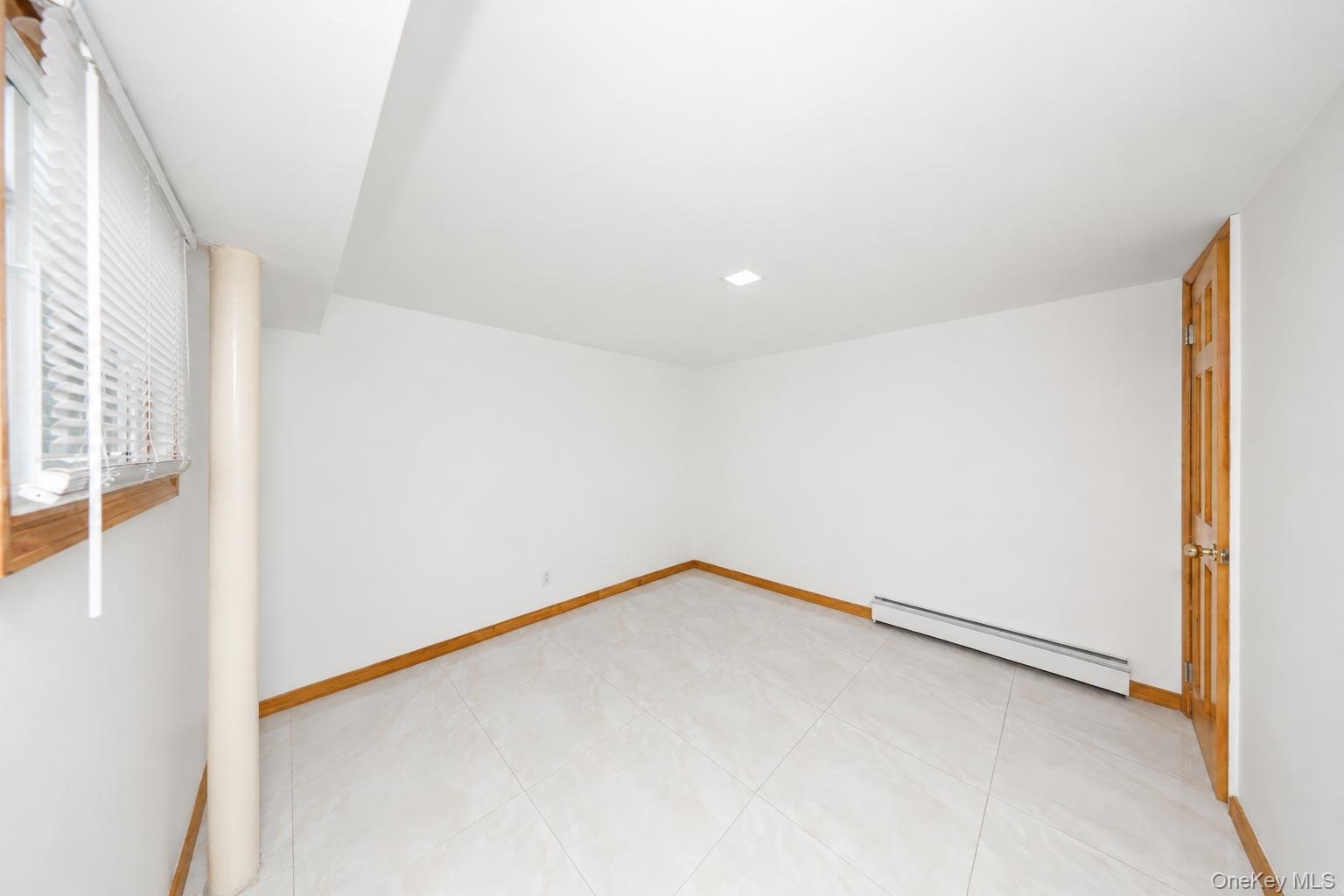 White tile flooring, wood trim, flush-mount ceiling lighting, and a wood-paneled door