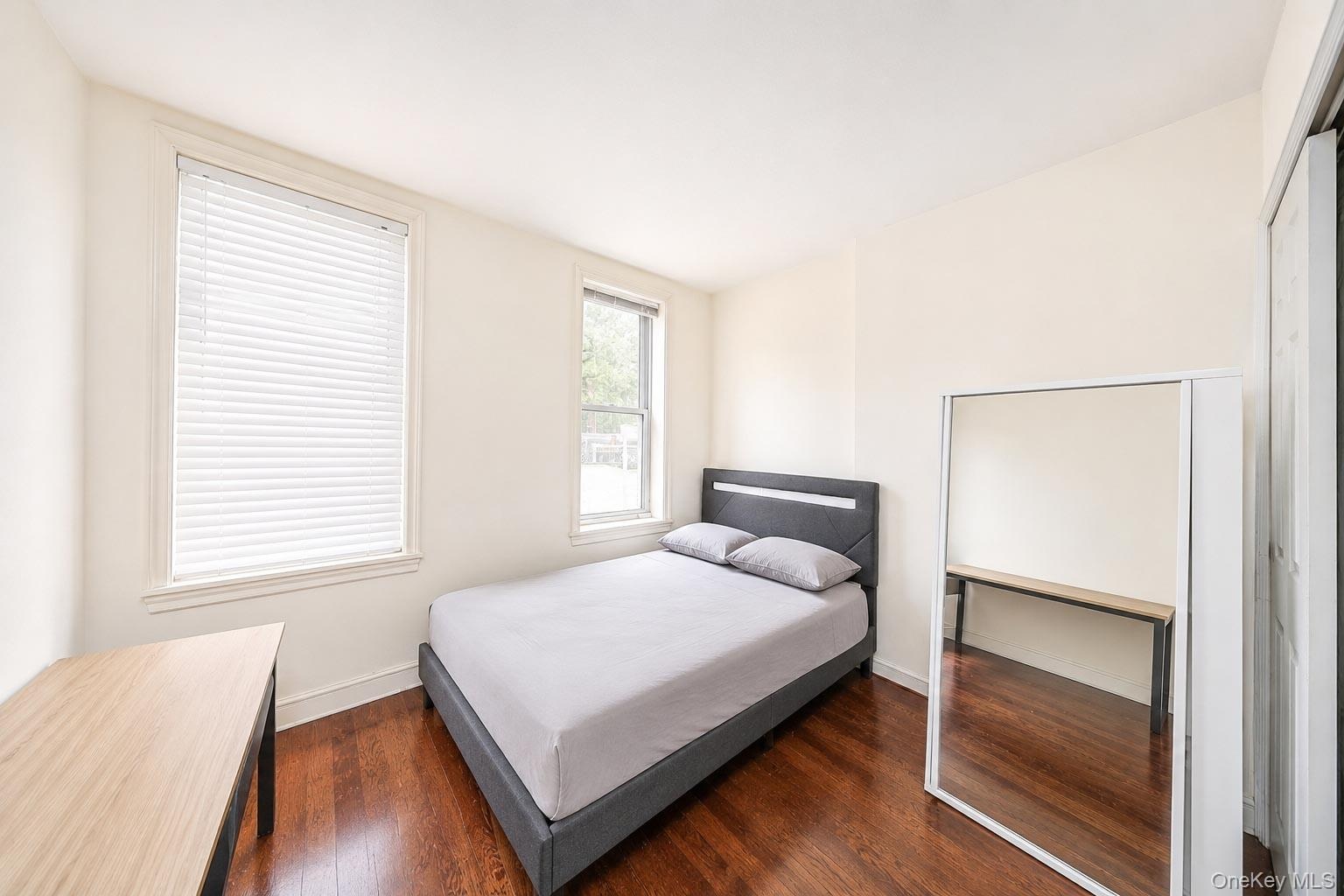 Hardwood flooring, two windows with blinds, and white walls