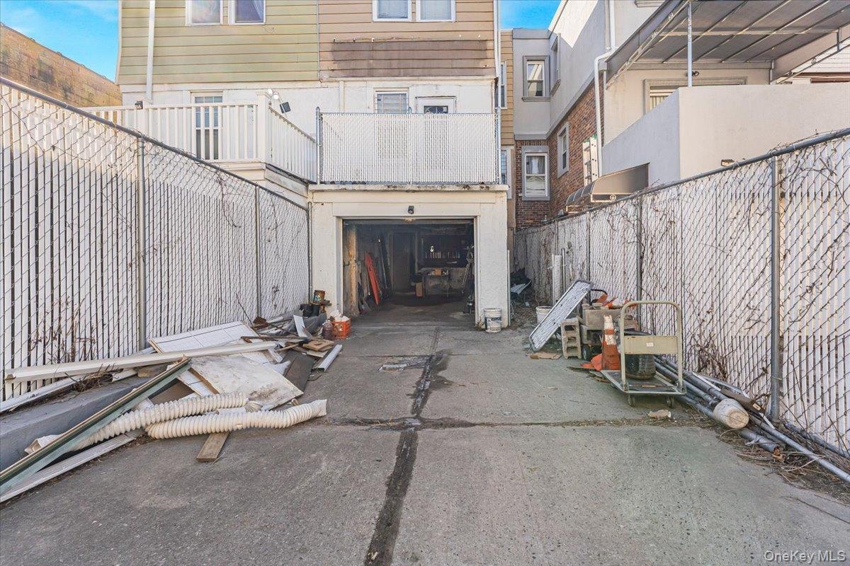 View of patio with a garage, concrete driveway, and fence