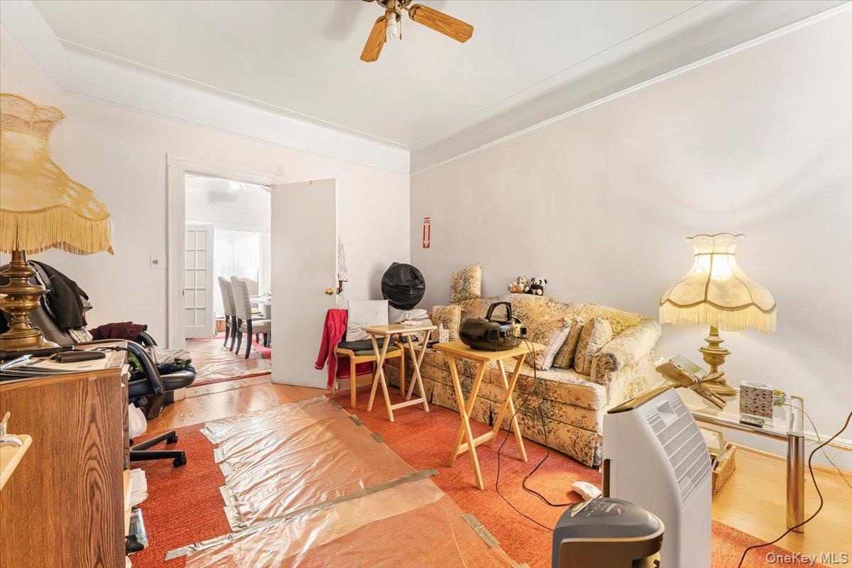 Office area with a ceiling fan, crown molding, and wood finished floors
