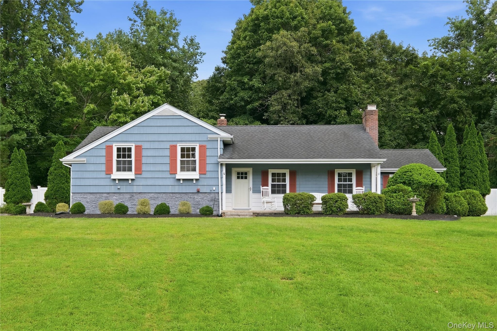 Single-story residence featuring blue cedar shingles , white trim, and red shutters