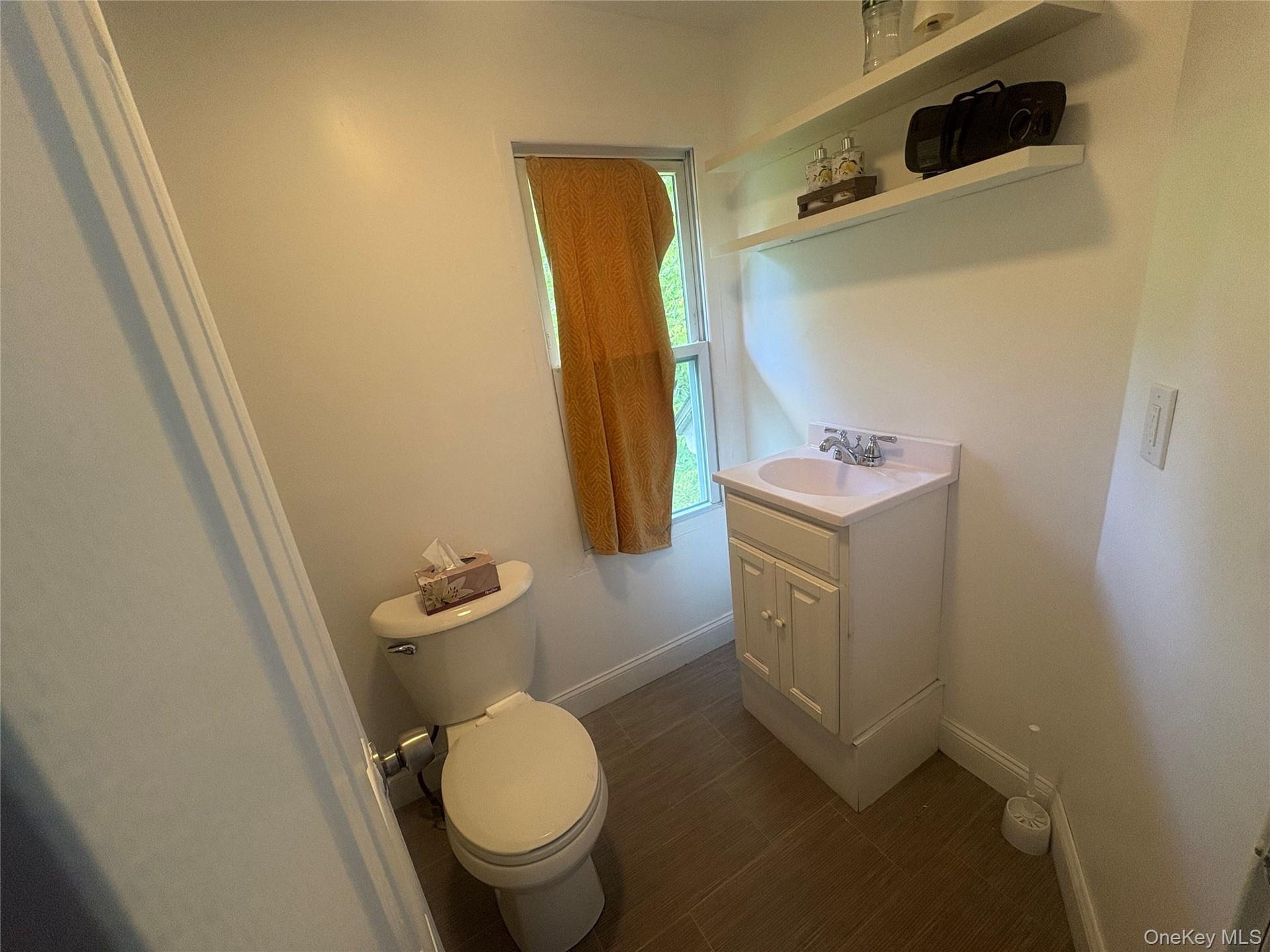 White vanity with an integrated sink and chrome faucet, accompanied by a toilet with a chrome flush lever