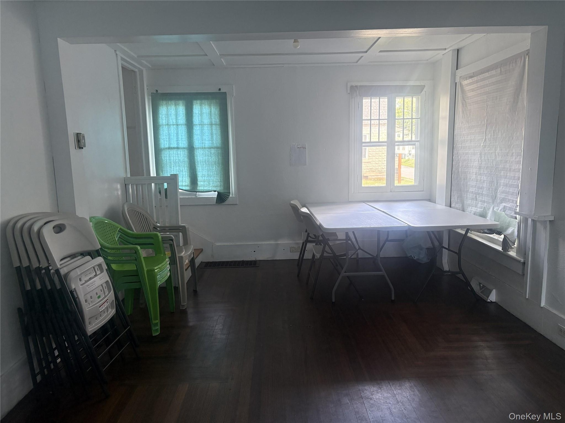 Hardwood flooring, painted white walls, white window trim, and a coffered ceiling