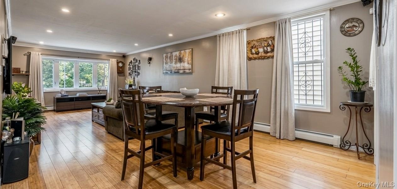 The spacious first-floor living and dining area features polished hardwood floors, modern recessed lighting, and clean neutral walls. A large round di