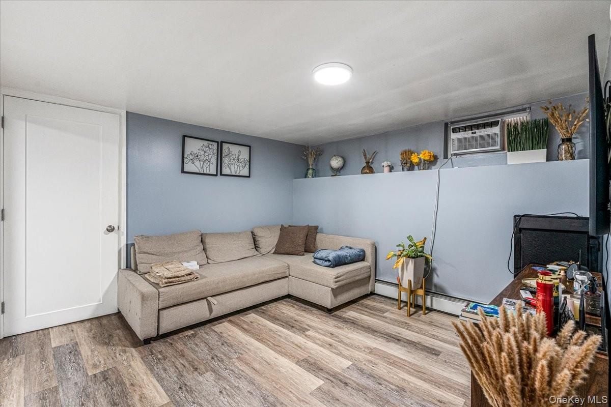 This spacious basement living room features beautiful wood-look flooring, cool blue walls, and a comfortable layout. It is a highly versatile space th
