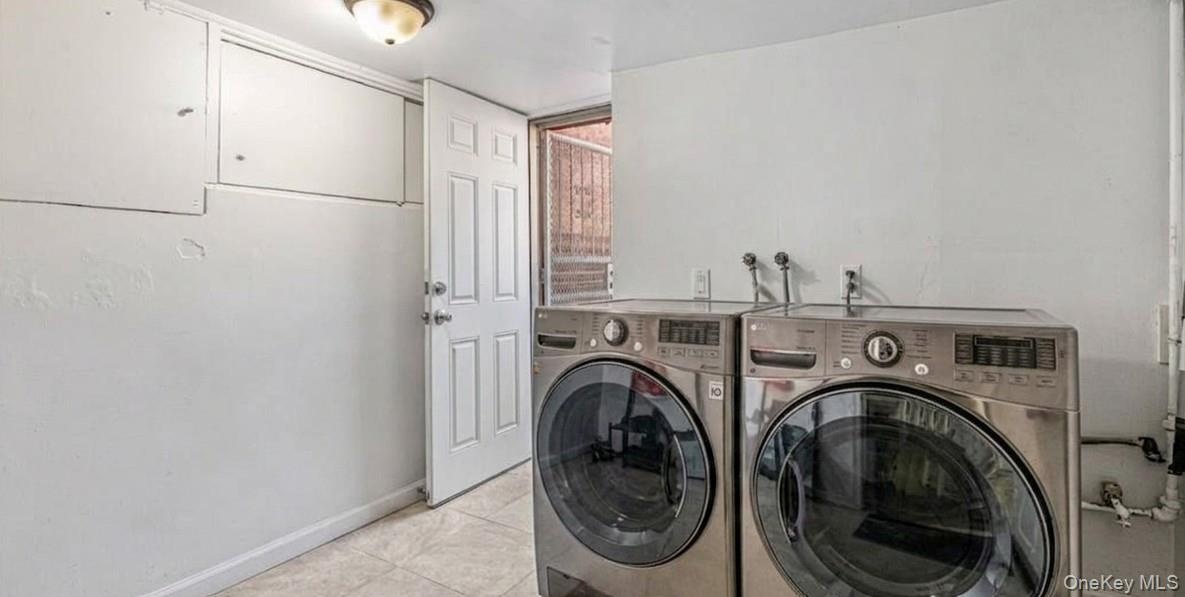 The spacious laundry room features a modern, side-by-side washer and dryer set with an efficient and clean white layout. The room offers plenty of spa